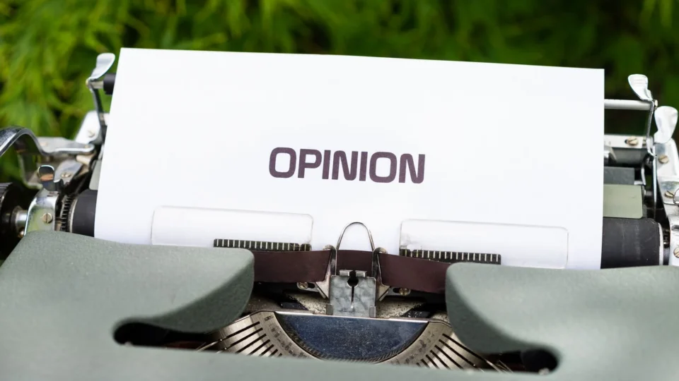 Close-up of a typewriter with paper showing the word 'Opinion' outdoors.