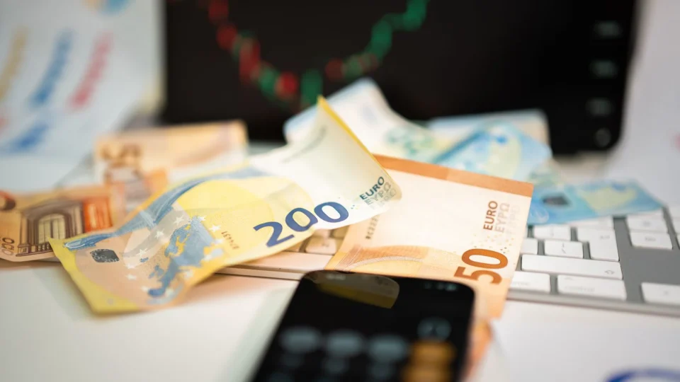 Euro banknotes and smartphone on desk, symbolizing finance and technology in business.