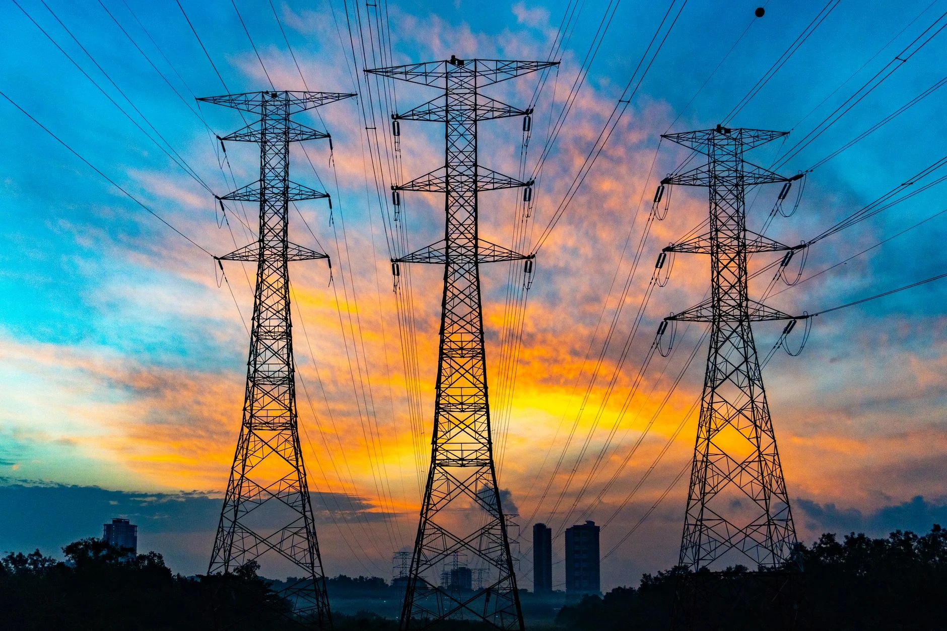 High voltage power lines against a dramatic sunset sky, symbolizing energy and technology.