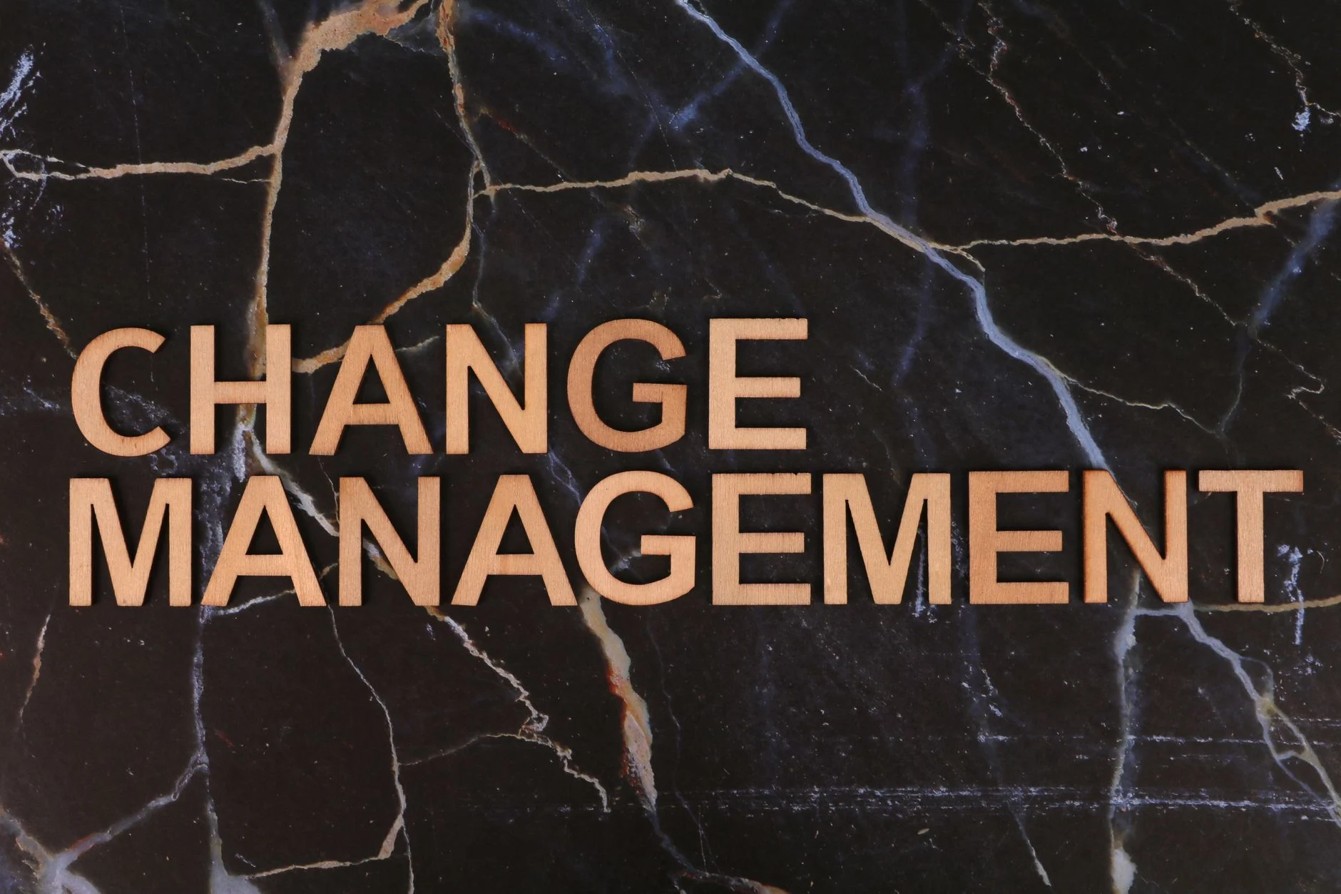 Wooden letters spelling 'Change Management' on a dark marble surface, emphasizing business change.