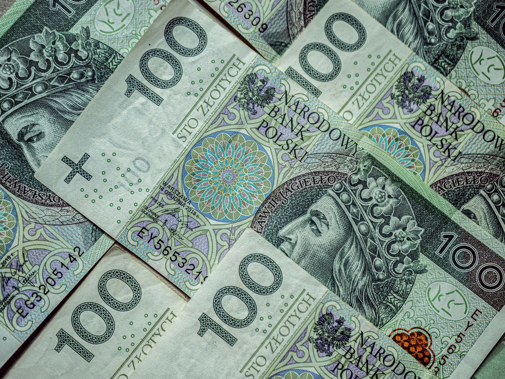 Close-up of multiple Polish 100 Zloty banknotes forming a financial background.