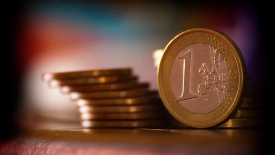 A close-up shot of stacked euro coins with a blurred colorful background, representing financial concepts.