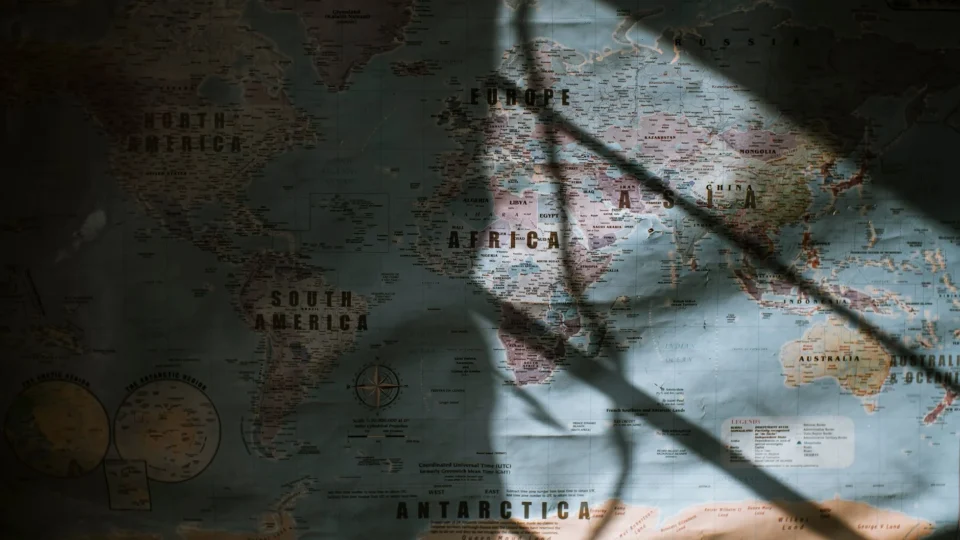 Aged world map with continents and oceans hanging on wall lit with sun