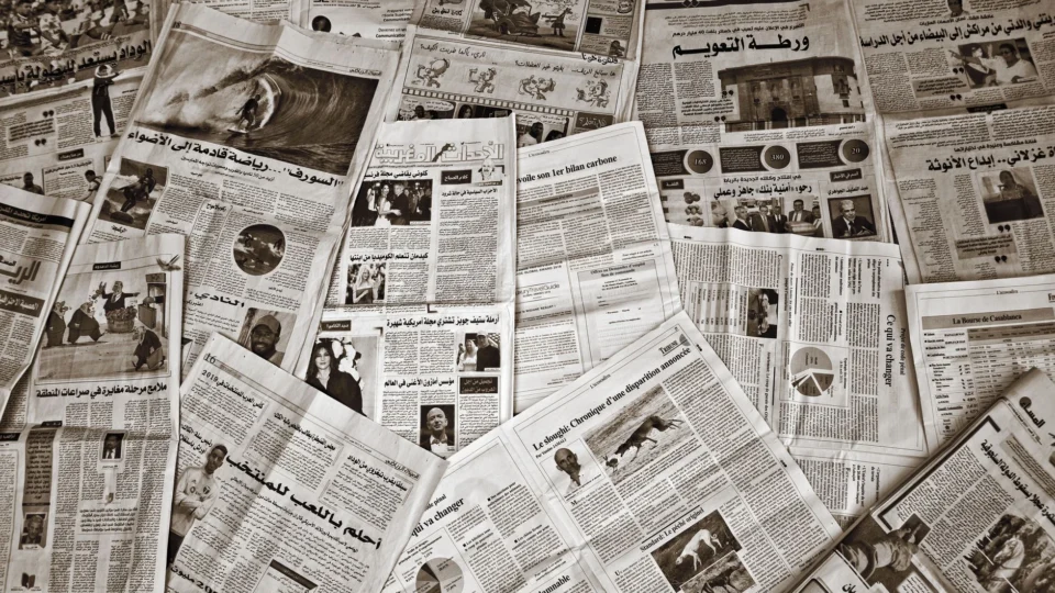 A variety of Arabic and French newspapers spread out, showcasing diverse articles and images.