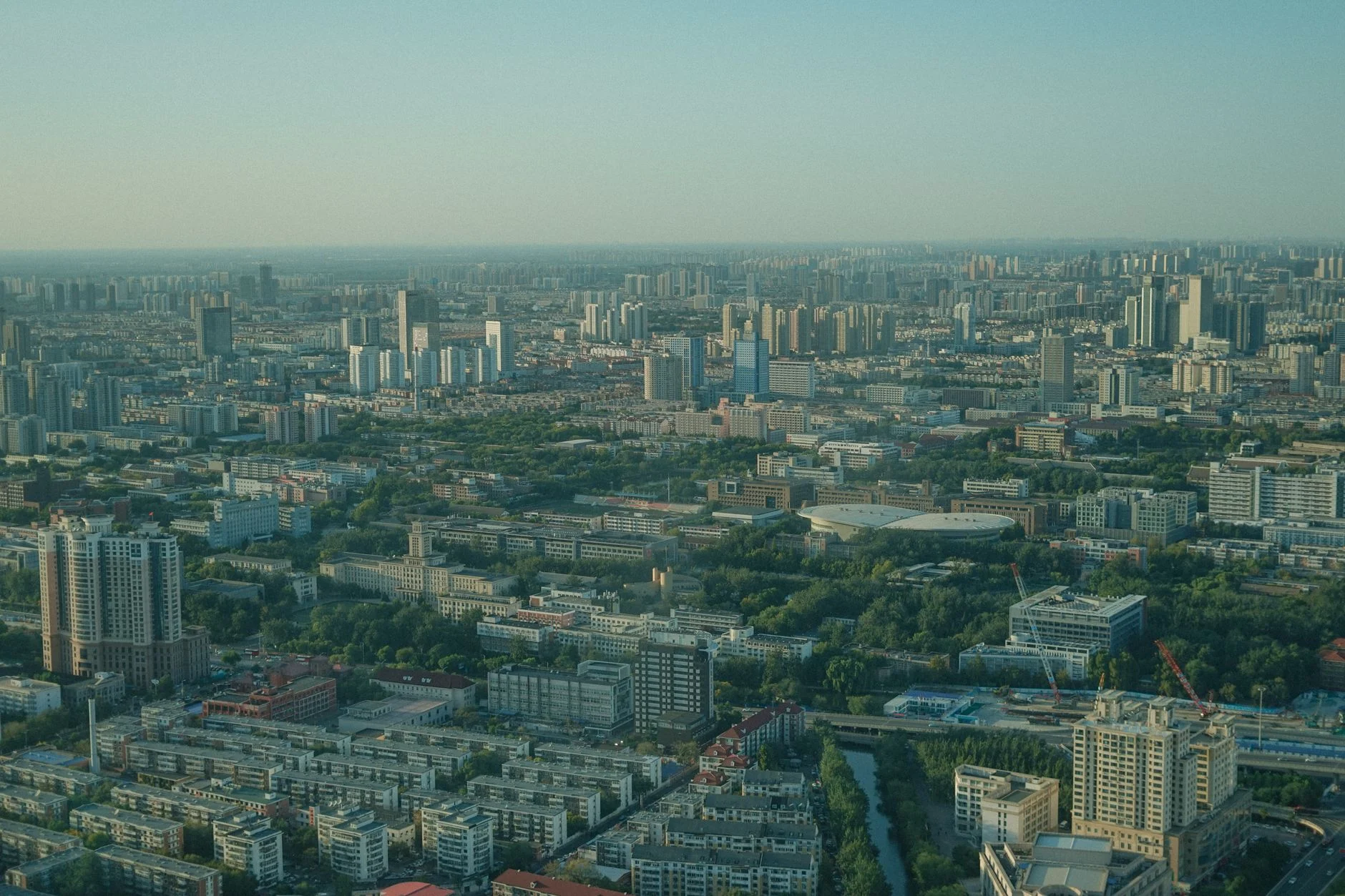 Expansive aerial view of a bustling cityscape with skyscrapers and lush greenery.