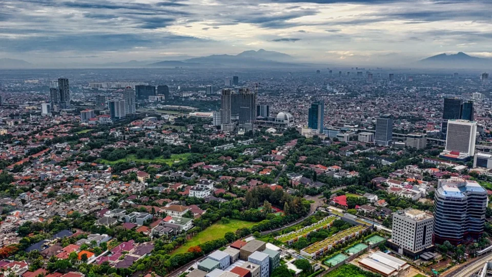 A stunning aerial view of Jakarta's sprawling cityscape with green spaces and high-rise buildings.