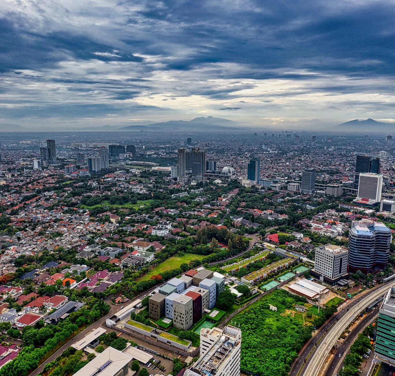 A stunning aerial view of Jakarta's sprawling cityscape with green spaces and high-rise buildings.