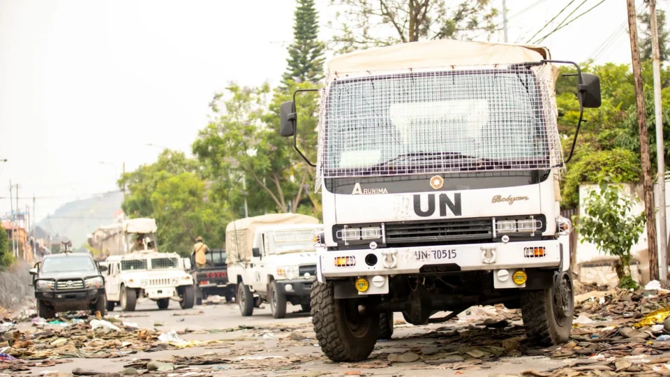 UN vehicles parked on a debris-covered road amid humanitarian efforts.