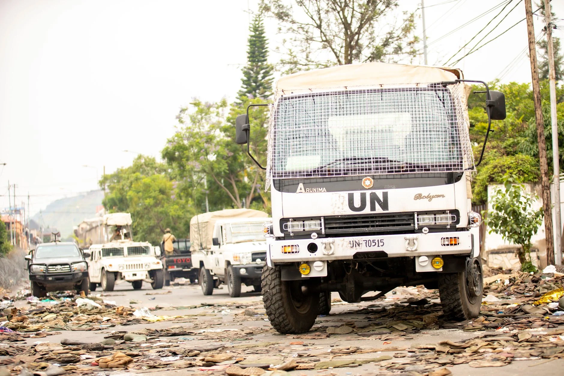 UN vehicles parked on a debris-covered road amid humanitarian efforts.