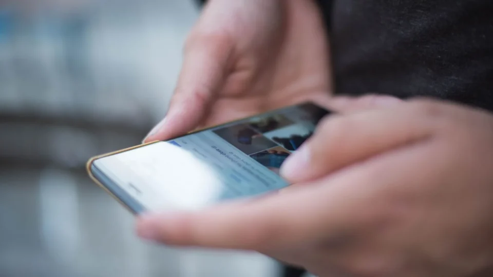 Close-up of hands using a smartphone with a touchscreen, emphasizing mobile technology.