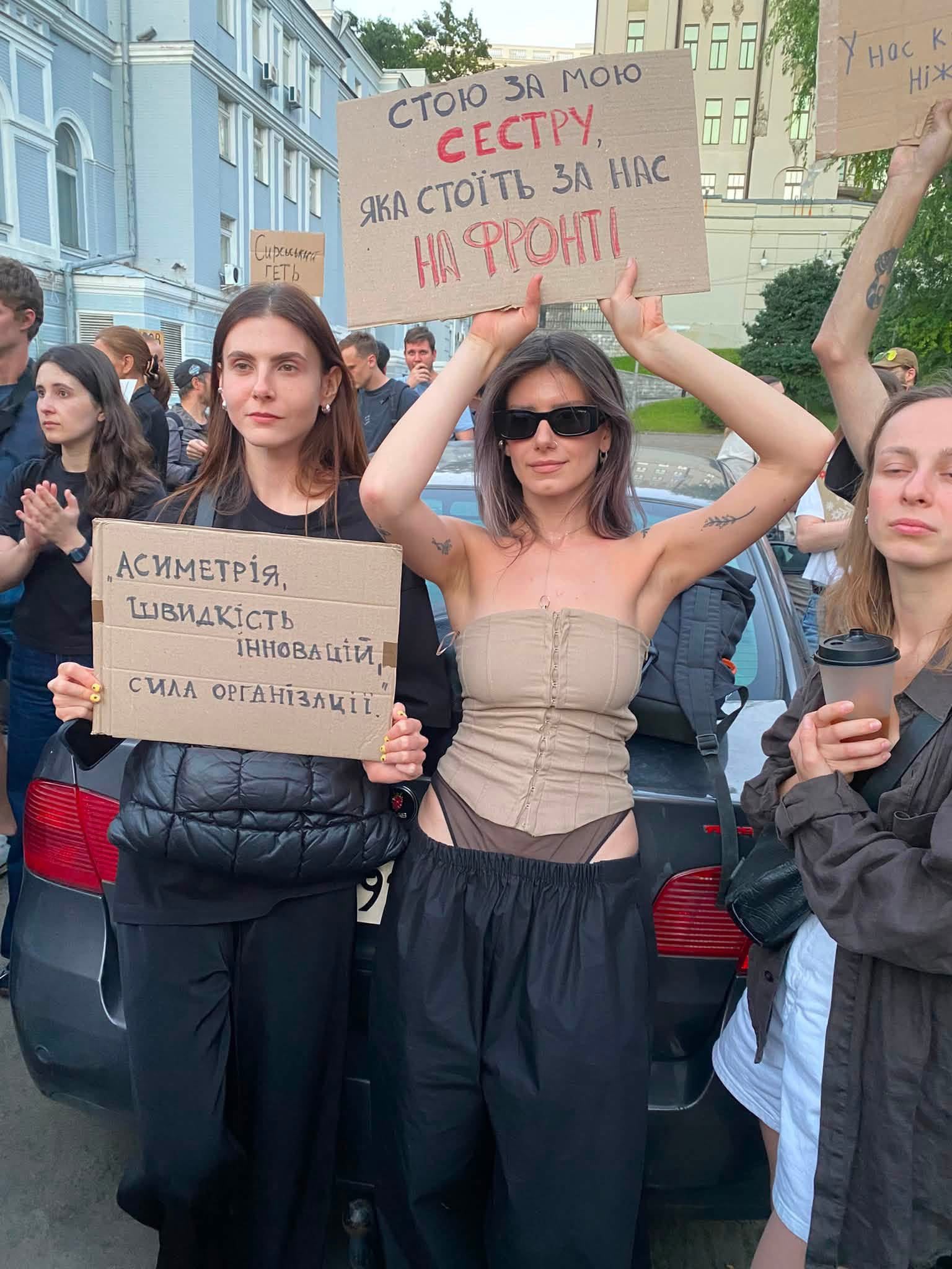 Young demonstrators holding handwritten cardboard signs in Kyiv