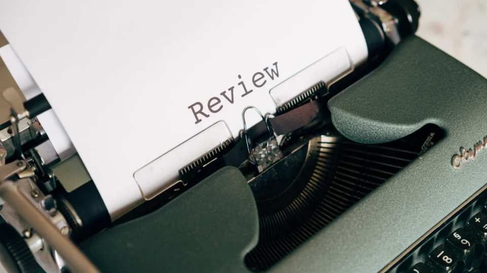 Close-up of an antique typewriter printing the word 'Review' on white paper.