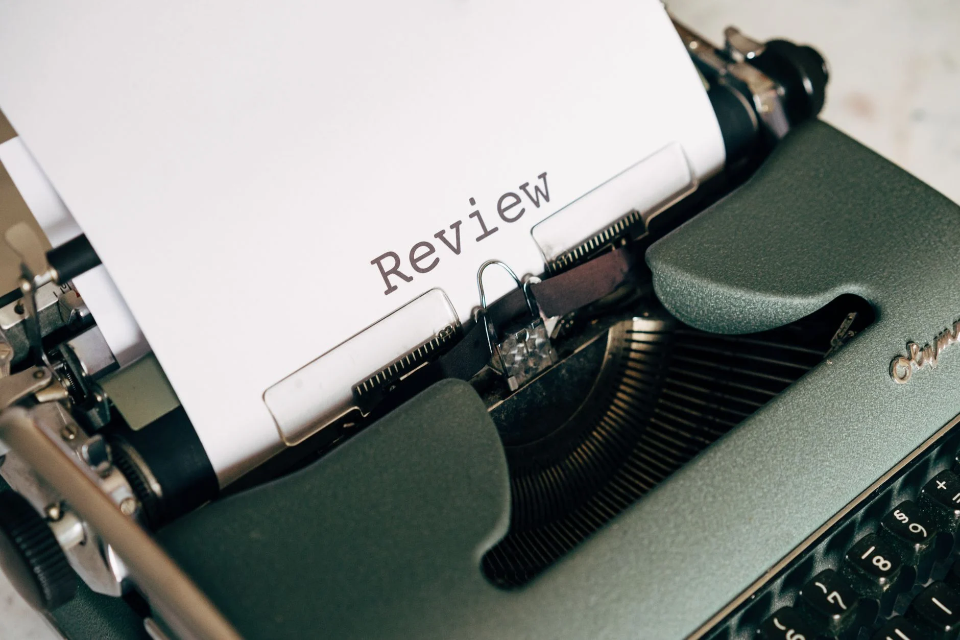 Close-up of an antique typewriter printing the word 'Review' on white paper.