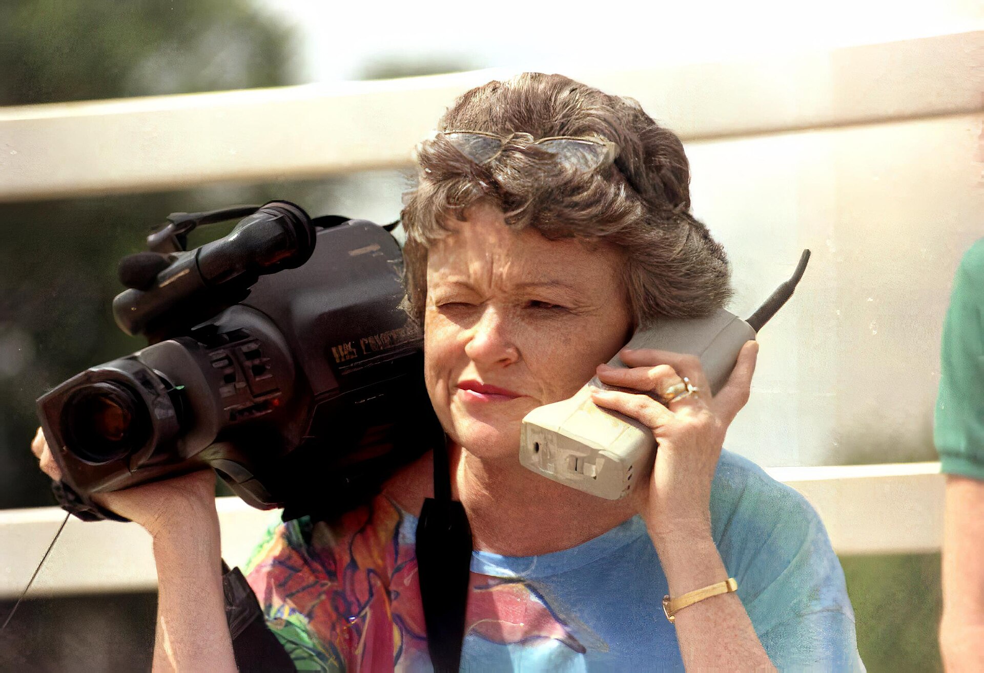 A journalist holding a video camera and a phone