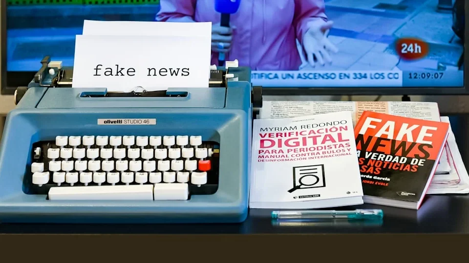 A blue typewriter sitting on top of a desk next to a tv