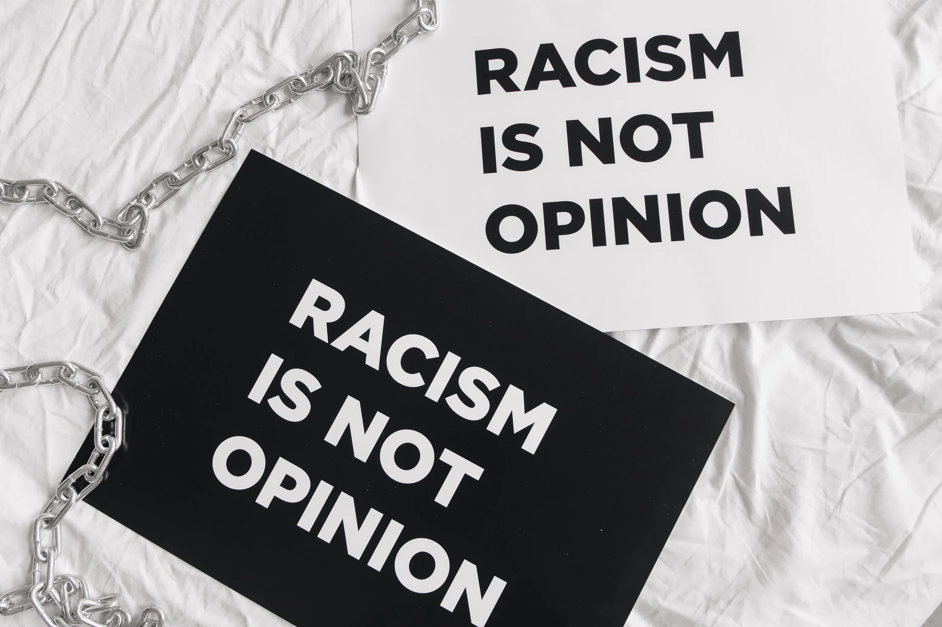 Black and white protest signs reading 'Racism is Not Opinion' on white fabric.