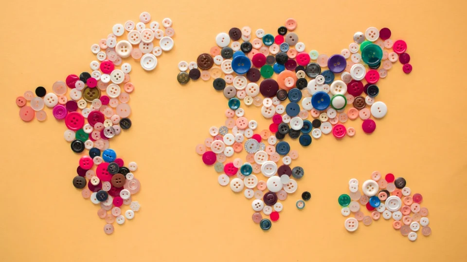 Top view of multicolored buttons of various size arranged on yellow background making world map
