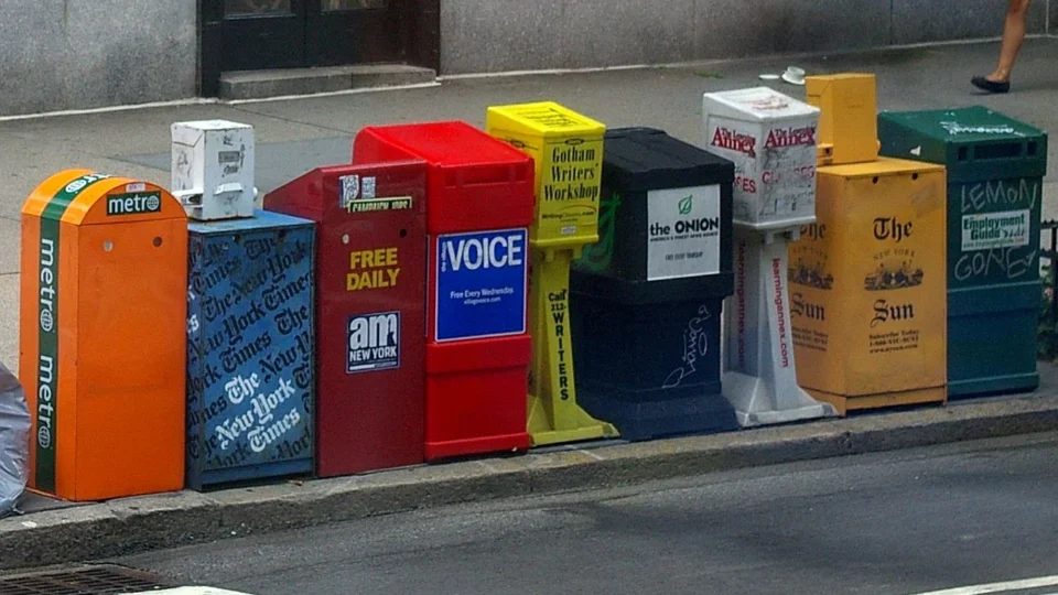Row of coin-operated newspaper vending machines on a street