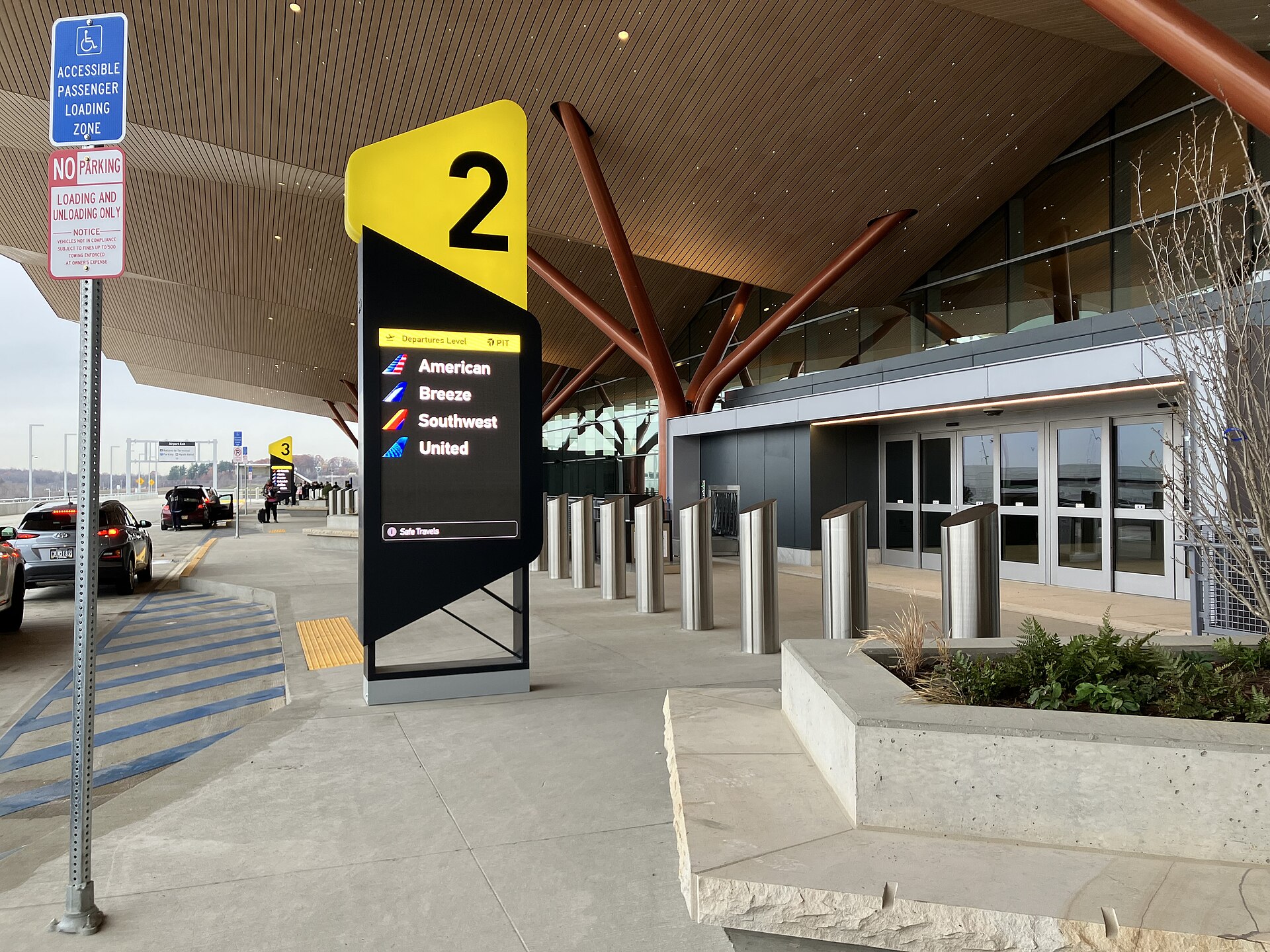 Cars lined up at an airport terminal passenger drop-off zone