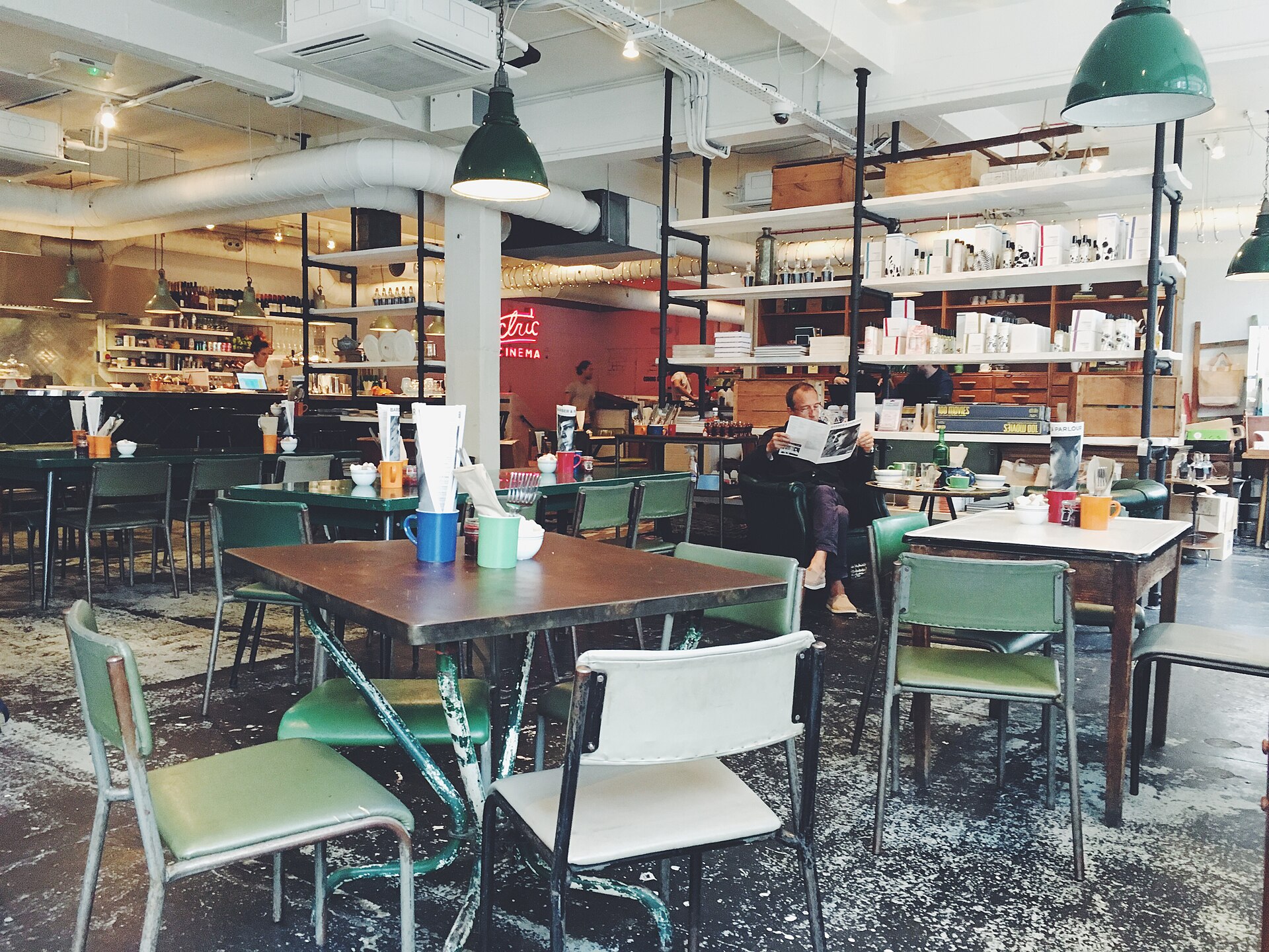 A man reading a newspaper alone in a café