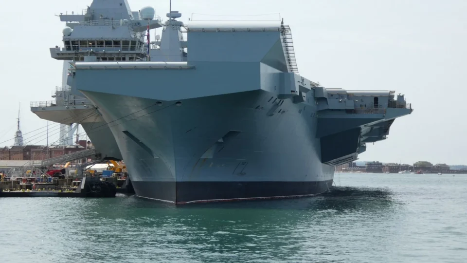 A Royal Navy aircraft carrier docked in Portsmouth, England, showcasing naval engineering.
