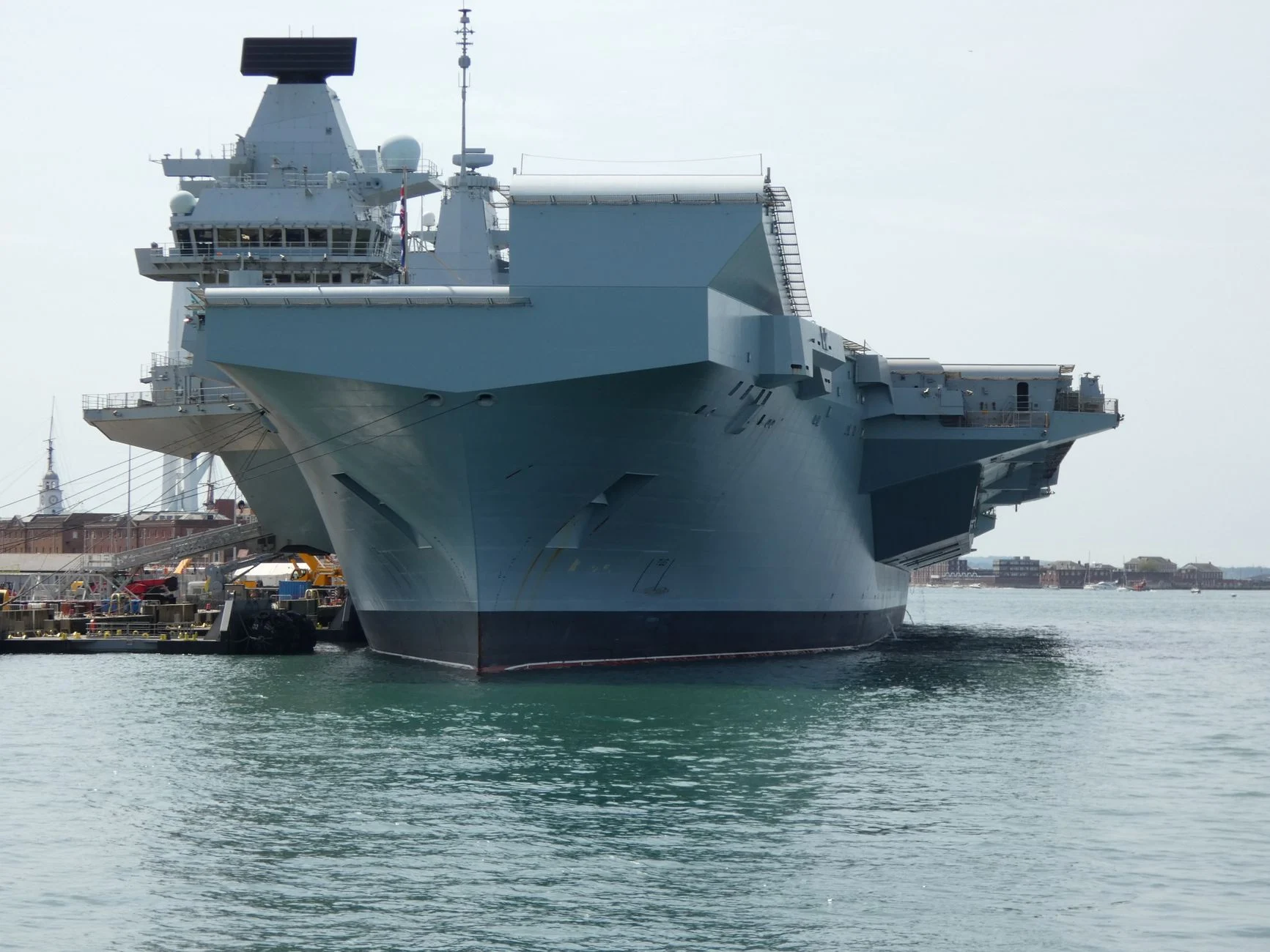 A Royal Navy aircraft carrier docked in Portsmouth, England, showcasing naval engineering.
