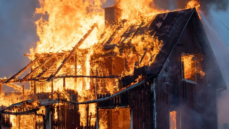 A house consumed by intense flames and smoke, capturing the power of fire.