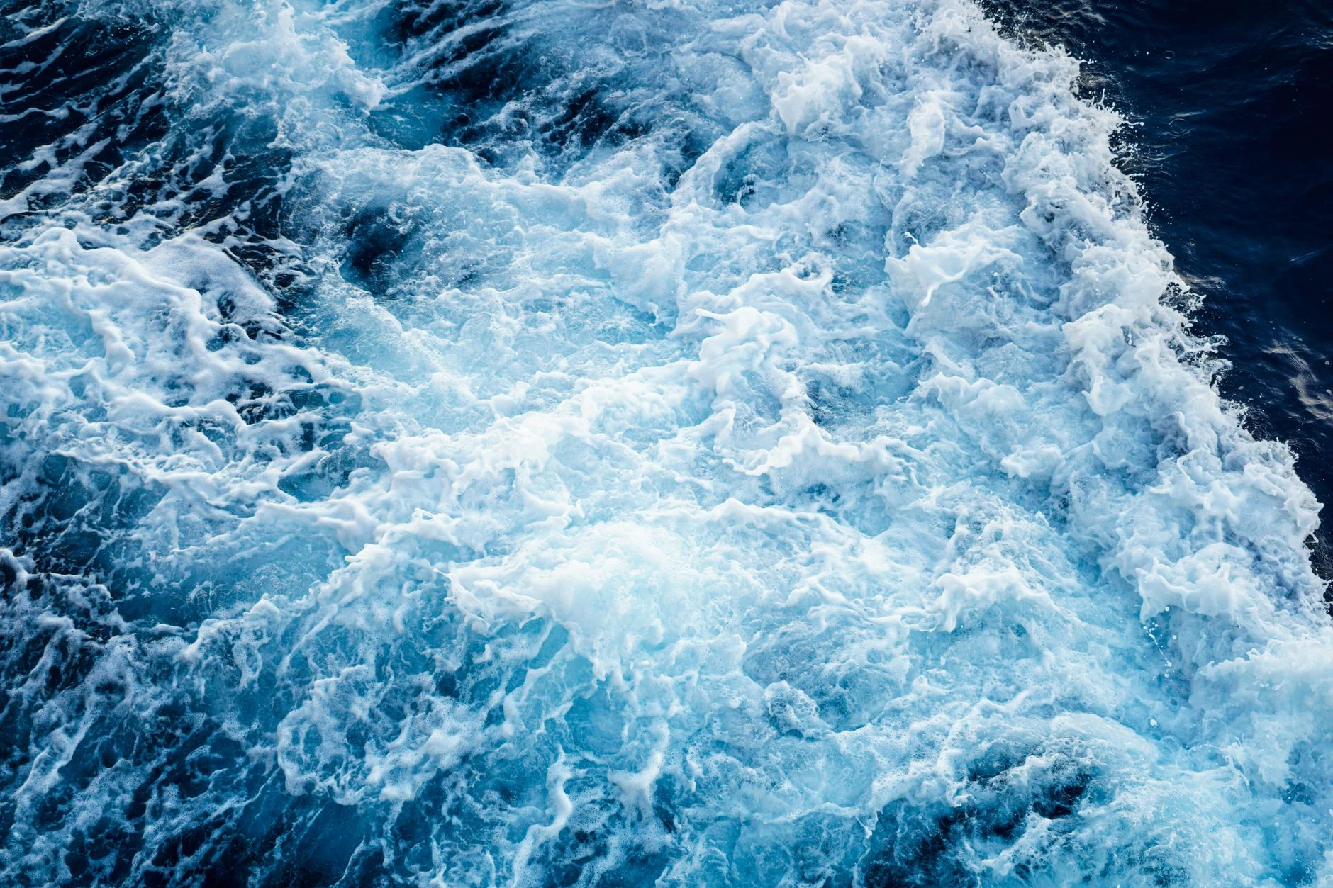 Aerial view of powerful ocean waves crashing, showcasing natural water patterns and textures.