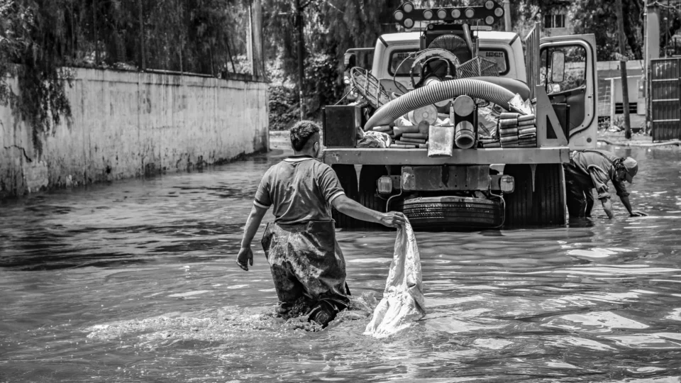 A black and white photo depicting flood cleanup efforts in an urban setting, showcasing resilience.