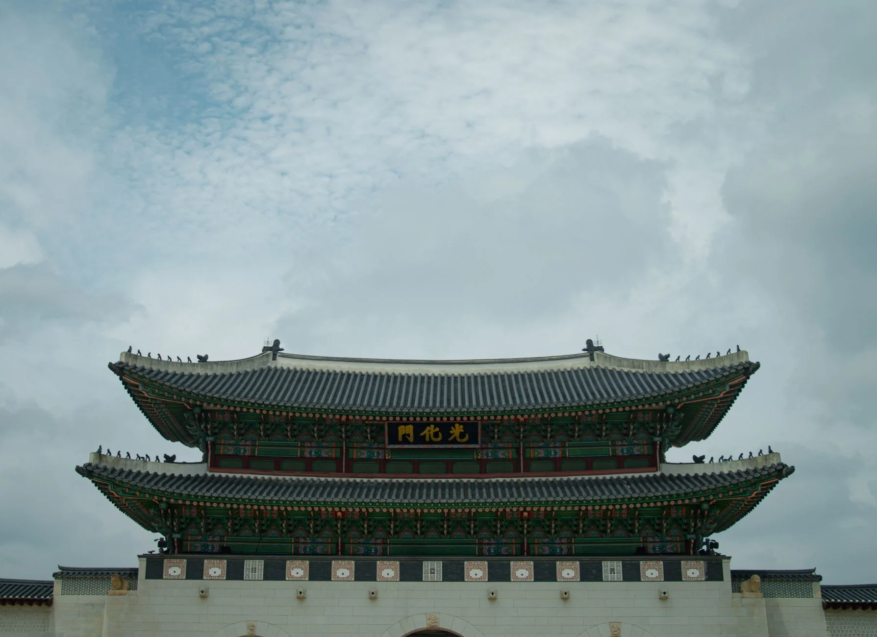 Historic Gyeongbokgung Palace main gate under a cloudy sky in Seoul, South Korea.