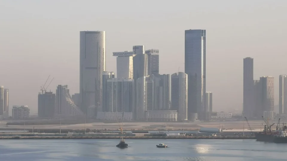 Panoramic view of Abu Dhabi's futuristic skyline with modern skyscrapers under hazy skies.