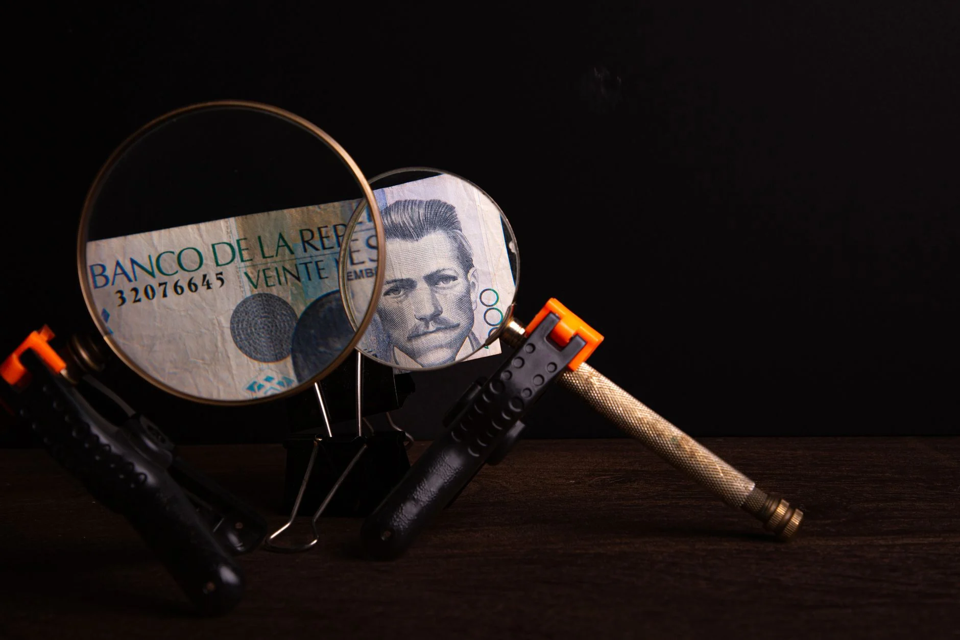Magnifying glasses highlighting details on a Banco de la República note in a creative setup.
