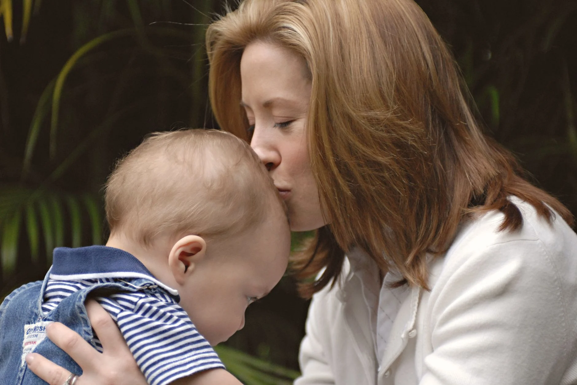 A tender moment between mother and baby, captured outdoors with warm, loving expressions.