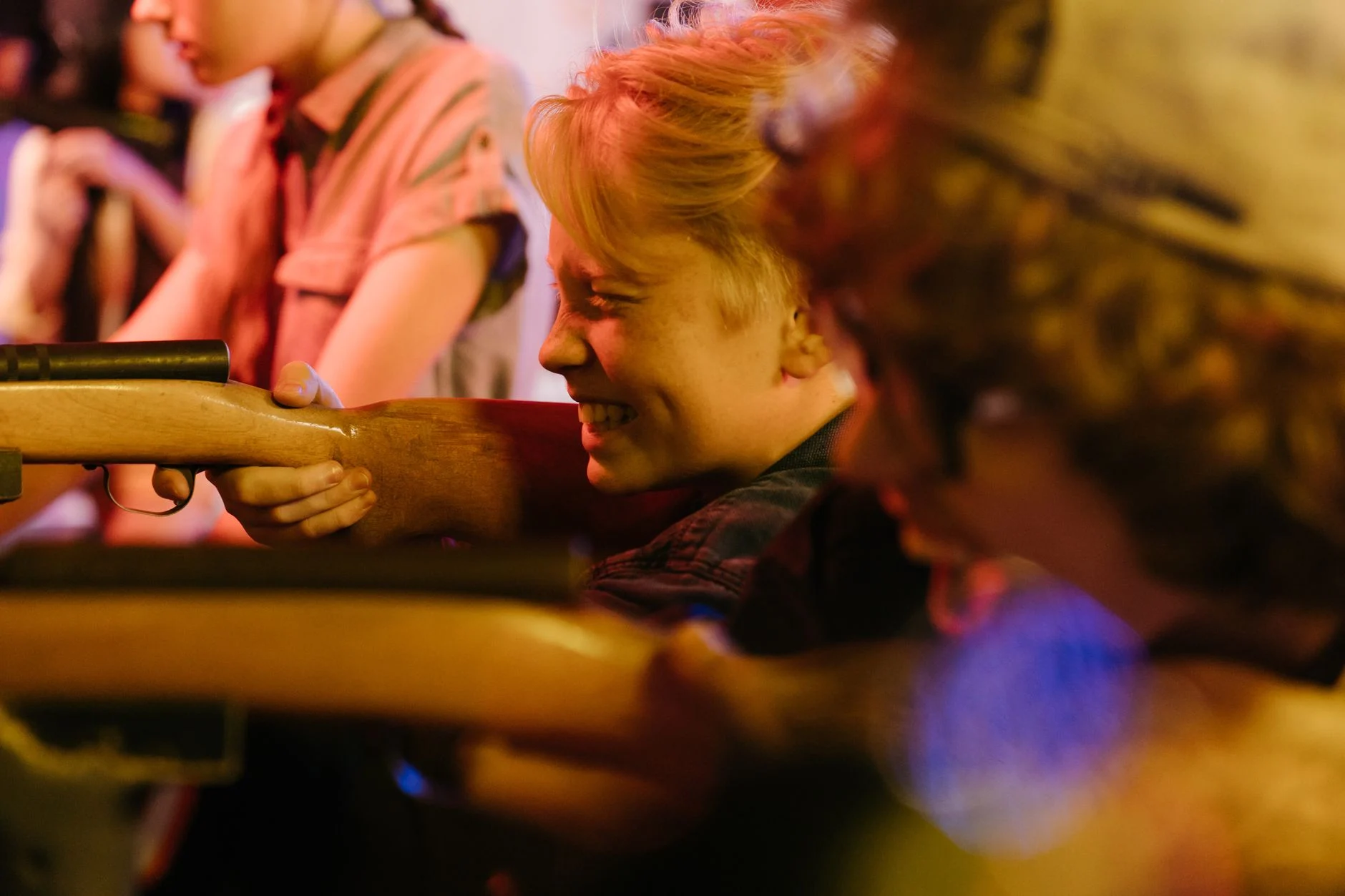 Group of teenagers playing at a retro shooting arcade, having fun together.