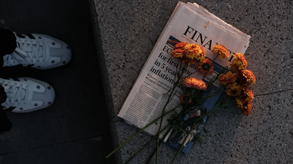 Bouquet of orange flowers atop a financial newspaper in soft evening light.
