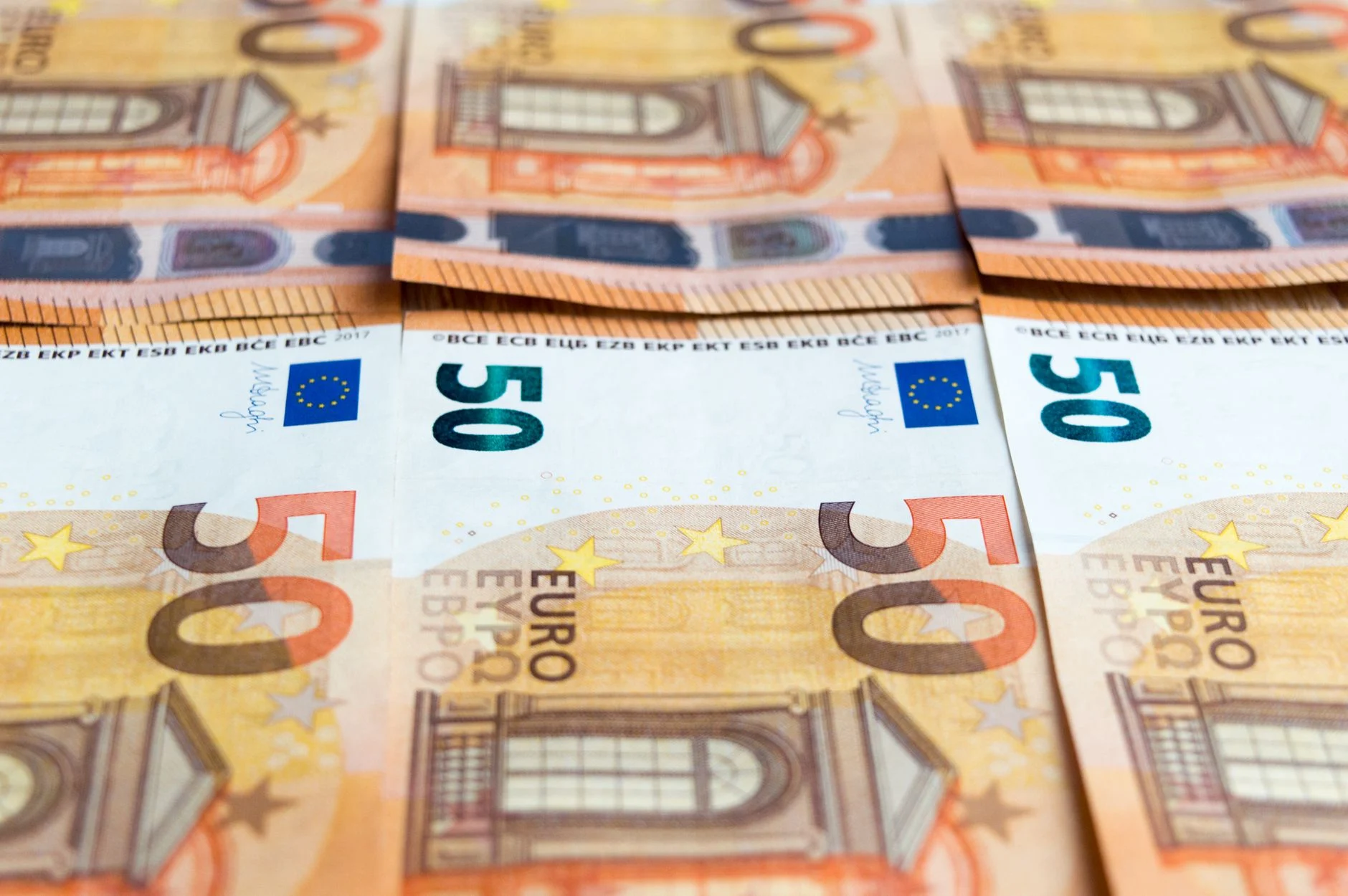 Detailed image of multiple 50 Euro bills stacked, showcasing currency design.
