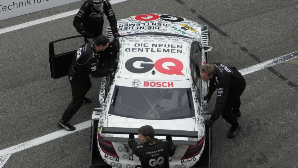A racing team pushes a Mercedes-Benz race car on the track at Zandvoort.