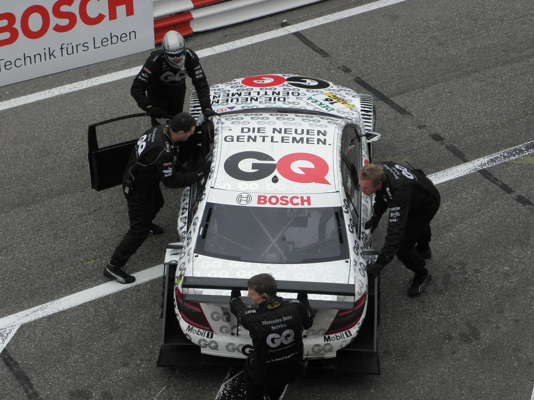 A racing team pushes a Mercedes-Benz race car on the track at Zandvoort.