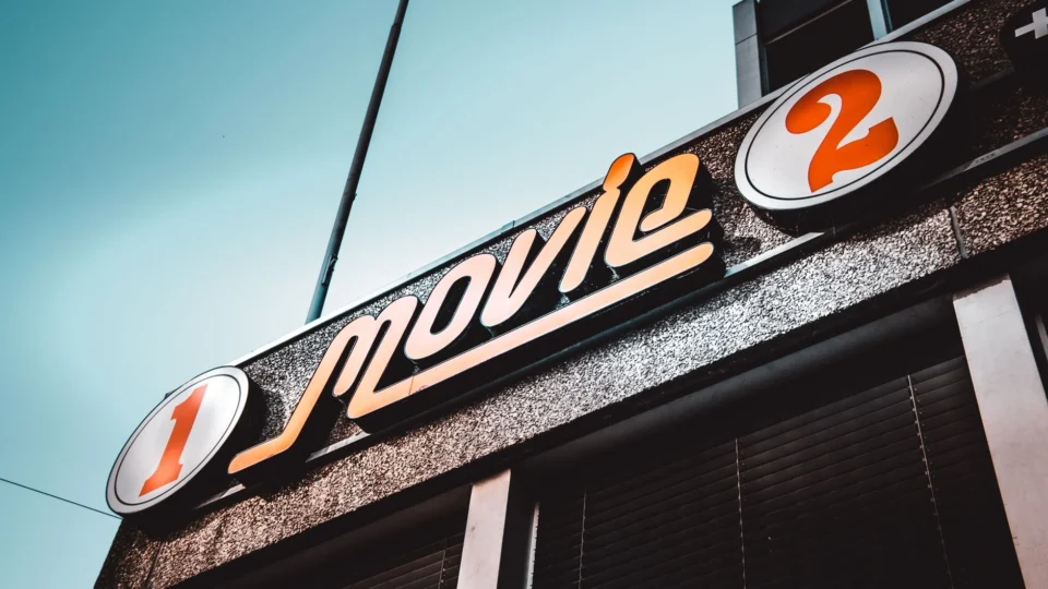 Low-angle shot of a vintage movie theater sign in Bern, Switzerland with a clear blue sky.