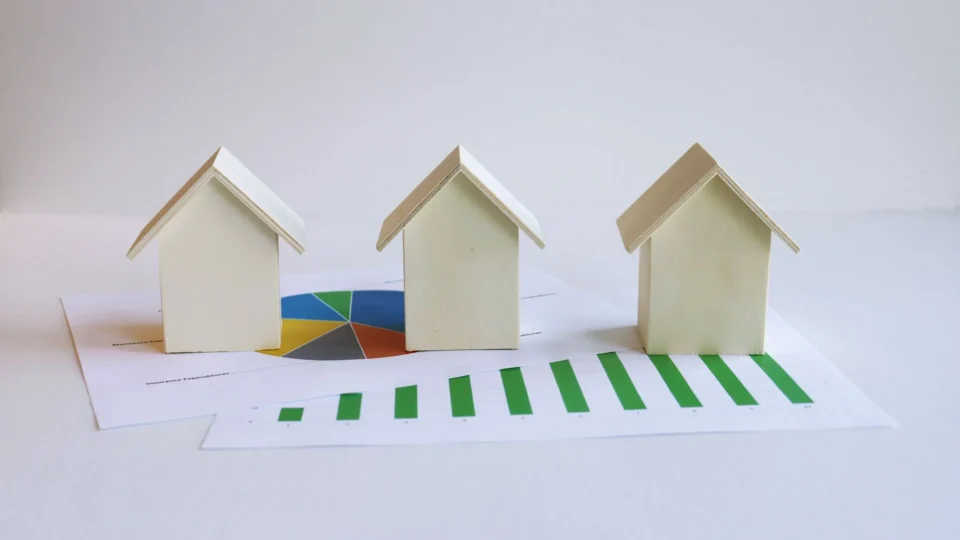 Wooden model houses on graphs depict real estate market analysis and trends.