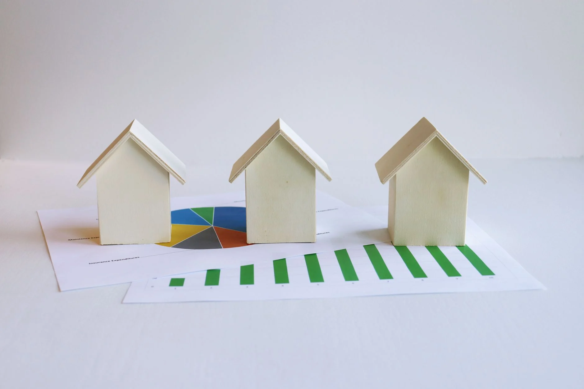 Wooden model houses on graphs depict real estate market analysis and trends.