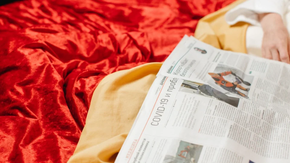 Close-up of a newspaper on a bed with COVID-19 headlines, conveying information and news.