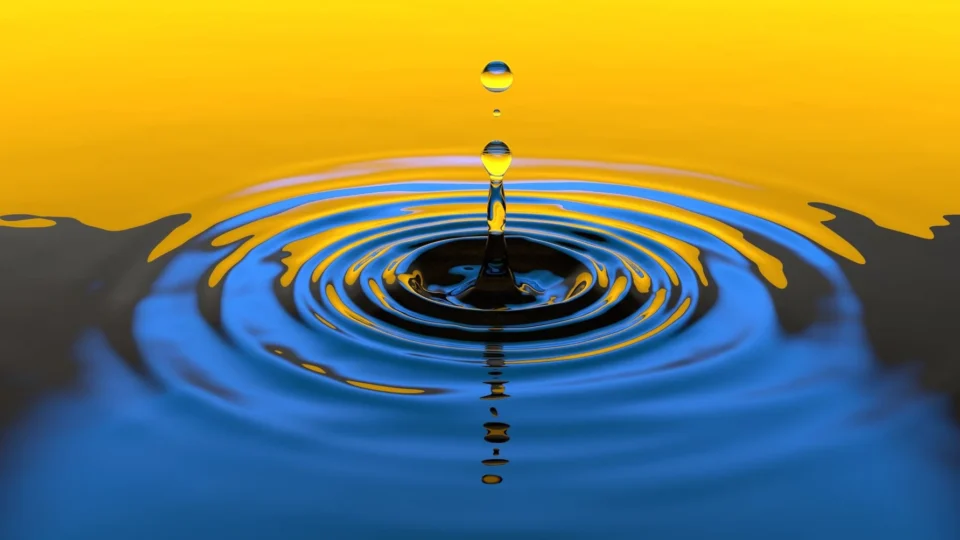 Close-up macro shot of a water droplet creating ripples with vibrant colors.