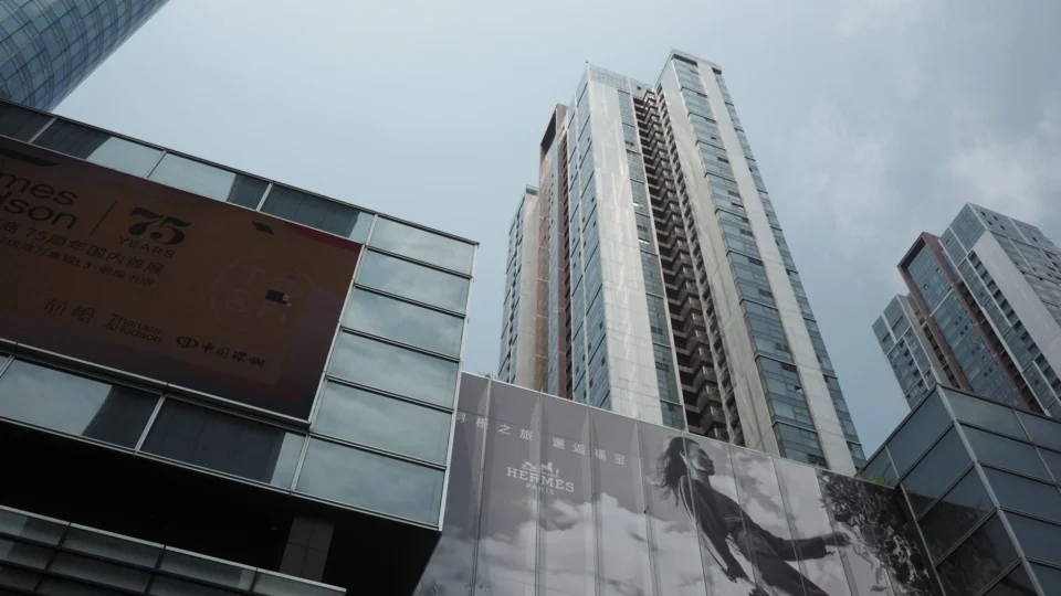 Skyscrapers with commercial billboards under a cloudy sky, depicting a modern urban scene.