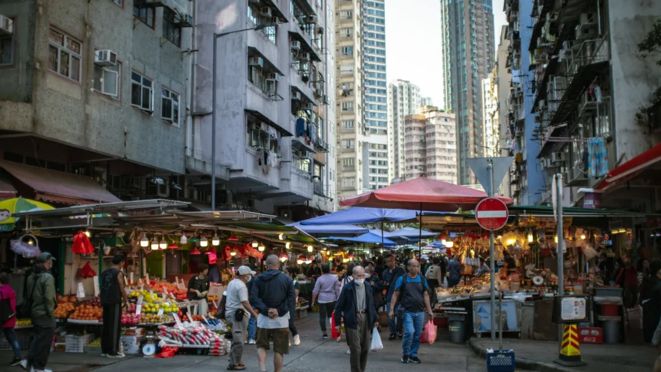 Vibrant outdoor market scene in Hong Kong, showcasing local urban life and high-rise buildings.