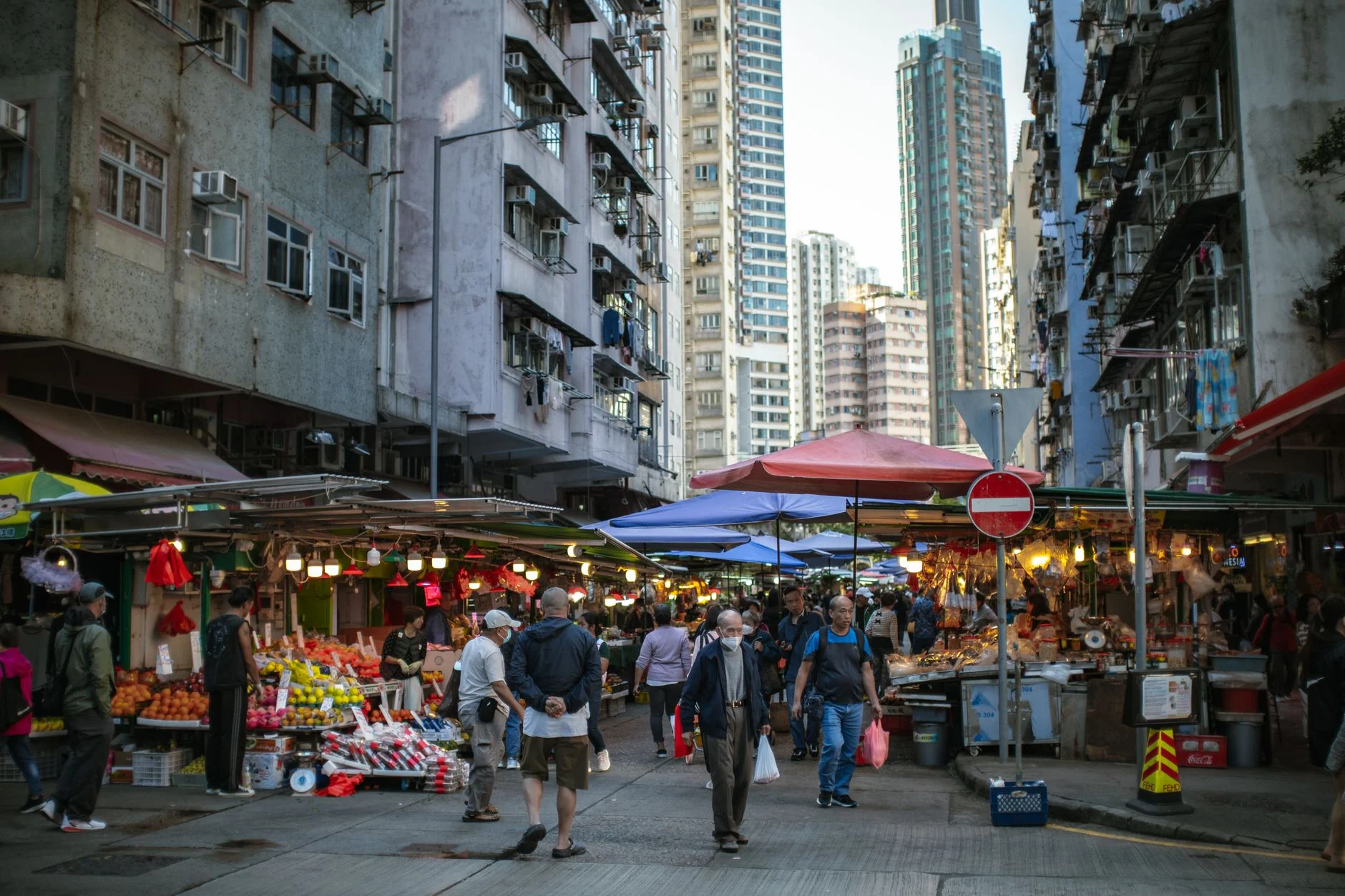 Vibrant outdoor market scene in Hong Kong, showcasing local urban life and high-rise buildings.