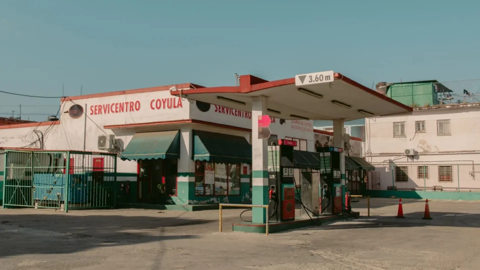 Old-fashioned gas station structure under a clear blue sky in daylight.