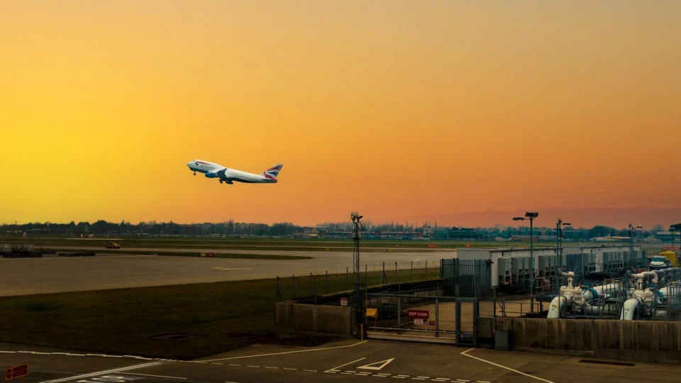 Airplane ascending during sunset at Heathrow Airport, capturing the vibrant sky.