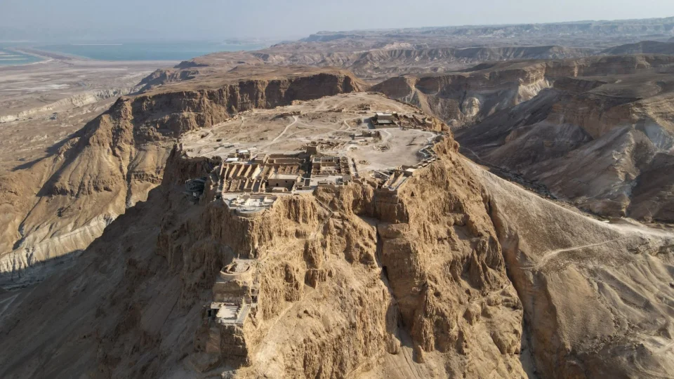Stunning aerial shot of the ancient Masada Fortress atop a rocky plateau in Israel's desert landscape.