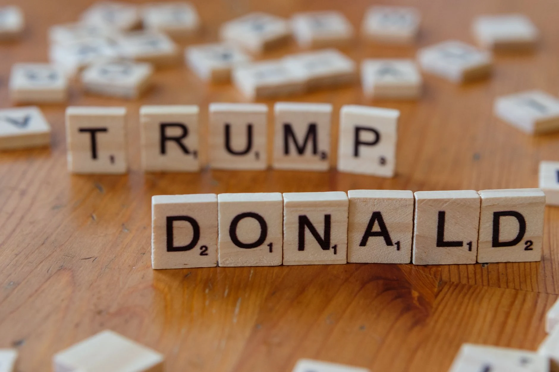 Close-up of Scrabble tiles spelling 'Donald Trump' on a wooden table.